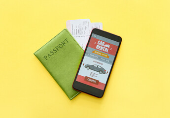 Mobile phone with open car rent app and passport on yellow background