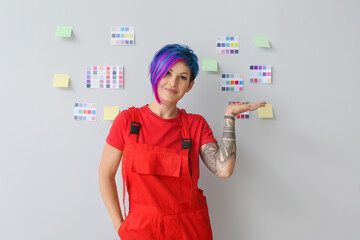Female painter with sticky notes and palettes on light background