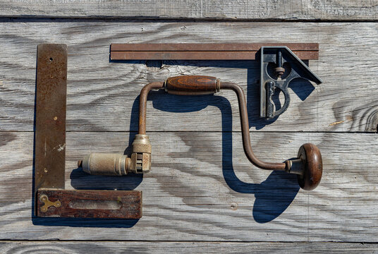 Group of three vintage tools: a brace and bit drill, antique carpenter's square and a combination square and level