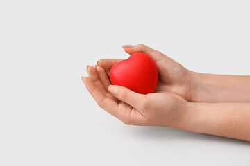 Female hands with red heart on light background. Donation concept