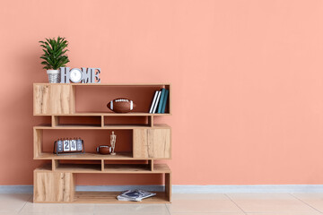 Shelving unit with rugby balls, books and decor near pink wall