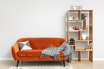 Stylish interior with sofa and bookshelf near wall in room