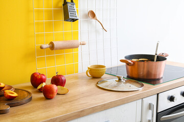 Ingredients for delicious compote and cooking pot on stove near color wall