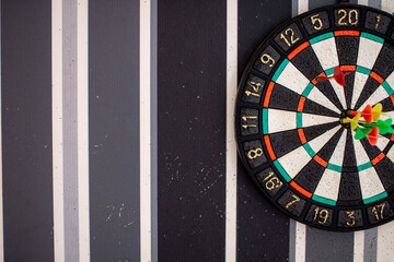 To hit the target with a dart, after many failures. Motivation to win. Holes in the wall from not hitting the target with a dart. A game of darts.