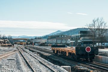 Obraz premium Train station of Grosuplje under construction. Visible workers on railway tracks in the distance and an empty flat bed waggon in the foreground.