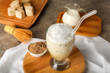 Board with glass of iced hojicha latte, chasen and powder on table