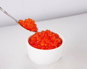 Red caviar in silver spoon isolated on the white background