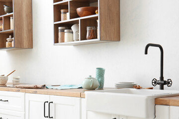 Teapot with cups on counter near light wall in kitchen