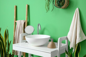 Interior of stylish bathroom with white table, sink and ladder