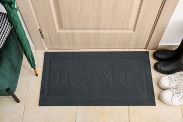 Black mat with word HOME near light wooden door