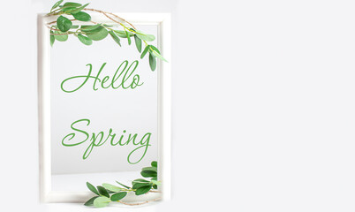Spring background - a spring composition of green branches and the inscription Hello Spring on a white background. Copy space. Frame