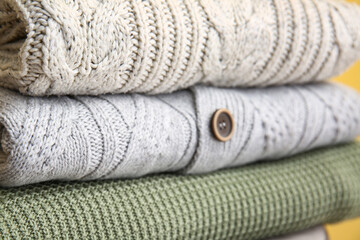 Stack of stylish warm sweaters, closeup