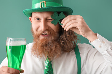 Happy bearded man with clover and glass of beer on green background. St. Patrick's Day celebration