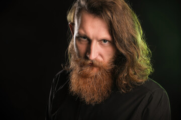 Portrait of young bearded man on black background