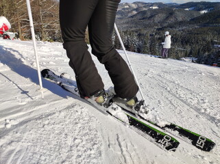 Skier on the ski slope. View of a skier overlooking a snowy slope. Turning on skis. Sunny winter day in the mountains. Winter sport.