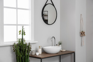 Table with sink and bath accessories near light wall in room