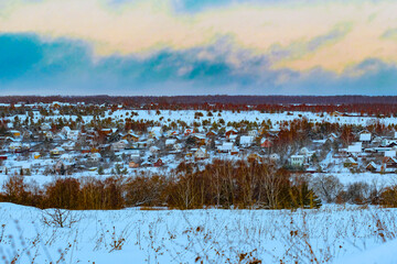 country winter landscape with the image of a village at sunset