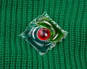 Washing gel capsule liquid powder on green knitted fabric background