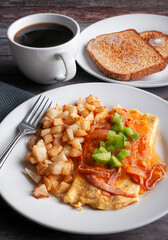 Omelette with cheese, red tomato and onion spicy salsa and cubes of green peppers on top with a side of squared deep fried potatoes black coffe and toasted bread with butter