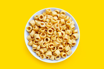 Crispy potato rings in white bowl on yellow background.