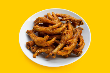 Fried chicken feet in white plate on yellow background.