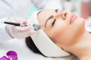 close-up view of a woman's head receiving diamond microdermabrasion treatment. skin care and...