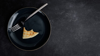 Empty plate with bitten off piece of bread and fork