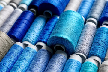 Closeup view of spools with grey and blue sewing threads