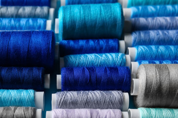 Spools with grey and blue sewing threads, closeup