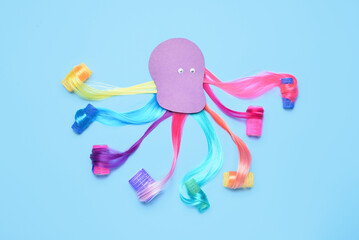 Octopus made of different hair strands and curlers on color background