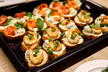 Bruschetta with shrimps on a black tray.