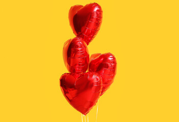 Beautiful heart-shaped balloons for Valentine's Day celebration on yellow background