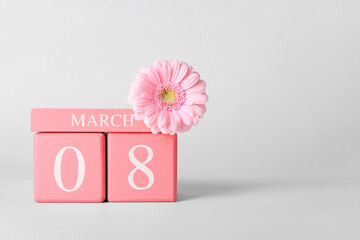 Calendar and flower for International Women's Day celebration on light background