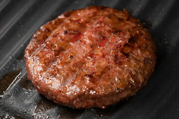 Process of roasting meat steak on barbecue grill plate. Cooking beef or pork patty. Raw cutlet for burger. Close-up photo.