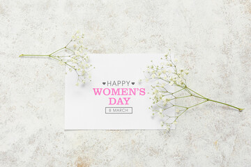 Greeting card with text HAPPY WOMEN'S DAY and gypsophila flowers on grunge background