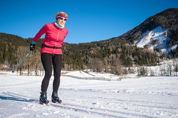 Caucasian middle aged woman, in ski wear and gear cross country style skiing.