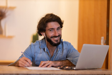 Young business man working at home with laptop and papers on desk. Home office concept.