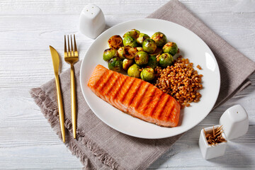 grilled salmon, brussel sprouts, spelt on a plate