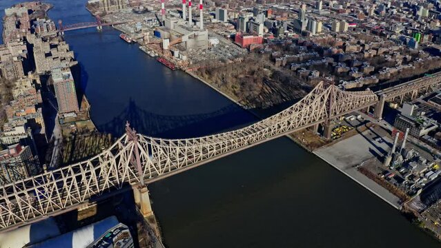 East River amidst buildings in city, drone flying backward from skyline