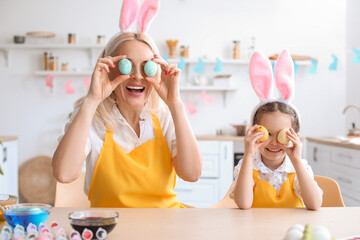 Little girl having fun with her grandmother while painting Easter eggs at home