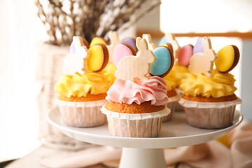 Stand with tasty Easter cupcakes on table, closeup