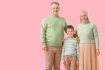 Fototapeta na wymiar Little boy with his grandparents in warm sweaters on pink background