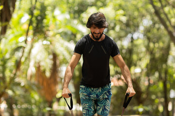 Strong man guy working out with elastic rubber bands at a park outdoors. Athlete male person during workout with additional sport equipment. High quality photo