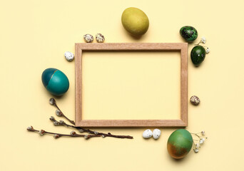 Composition with photo frame, Easter eggs and pussy willow branches on beige background
