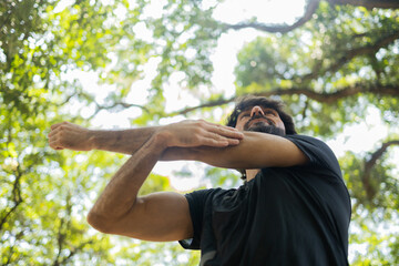 Young guy stretching before workout at a park outdoors. Athlete male person prepping for workout. High quality photo.