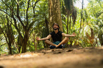 young man meditating. practice of yoga and meditation on a sunny. day at a park. High quality photo.