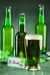 Glass and bottles of beer on green background. St. Patrick's Day celebration