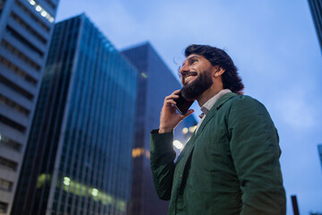 View of young man using a smartphone at night time with city view landscape in the background. High quality photo