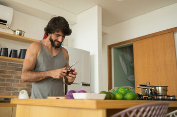 Happy and healthy young man meal prepping whole vegetarian meal in the kitchen. High quality photo