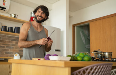 Happy and healthy young man meal prepping whole vegetarian meal in the kitchen. High quality photo